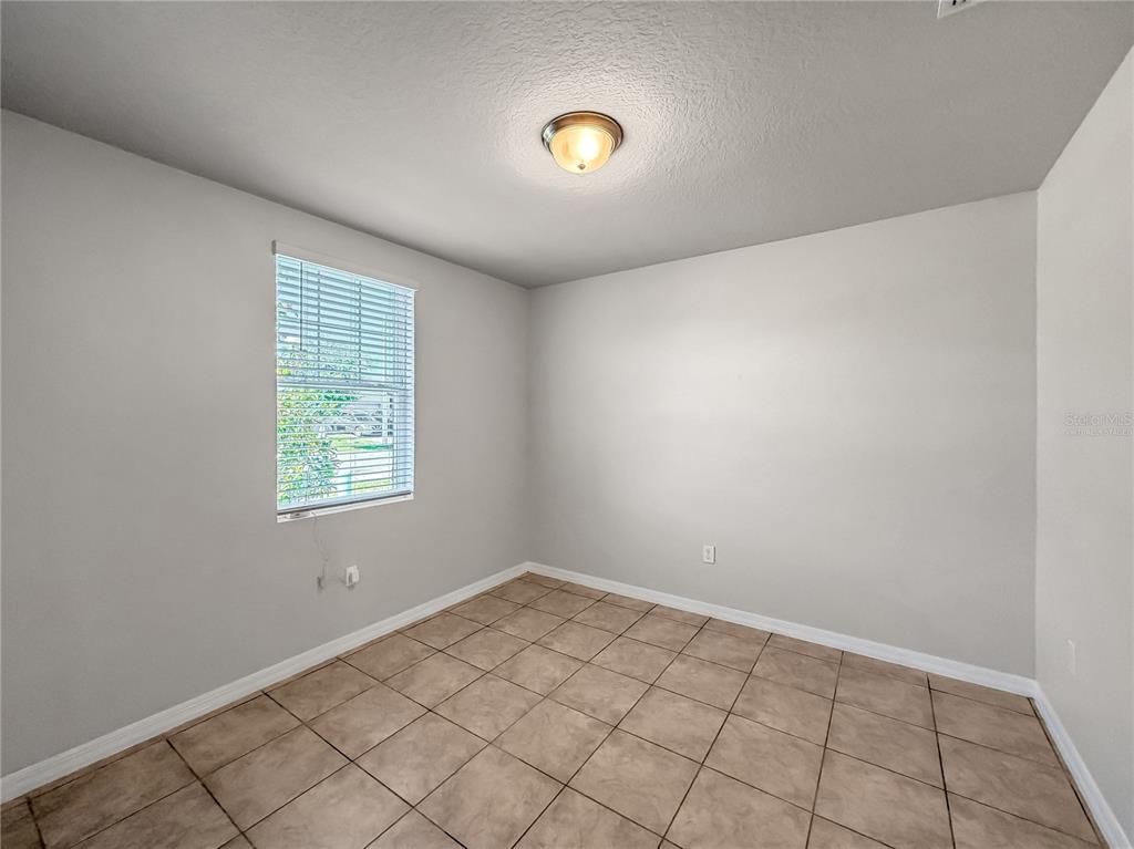 An empty room features light-colored walls, a single window with blinds, and tiled flooring — 868 TETON STREET, HAINES CITY, FL