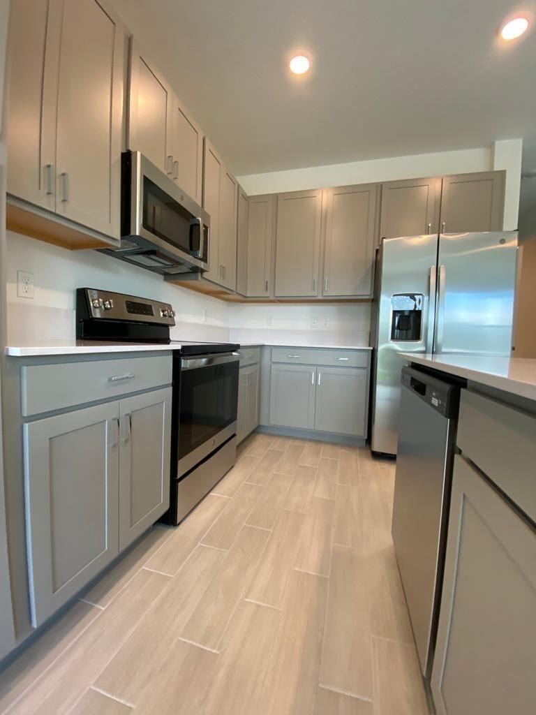 A kitchen with grey cabinets, stainless steel appliances, and light-colored tile flooring — 4946 Navali Drive, Lake Worth FL 33467, LAKE WORTH, FL