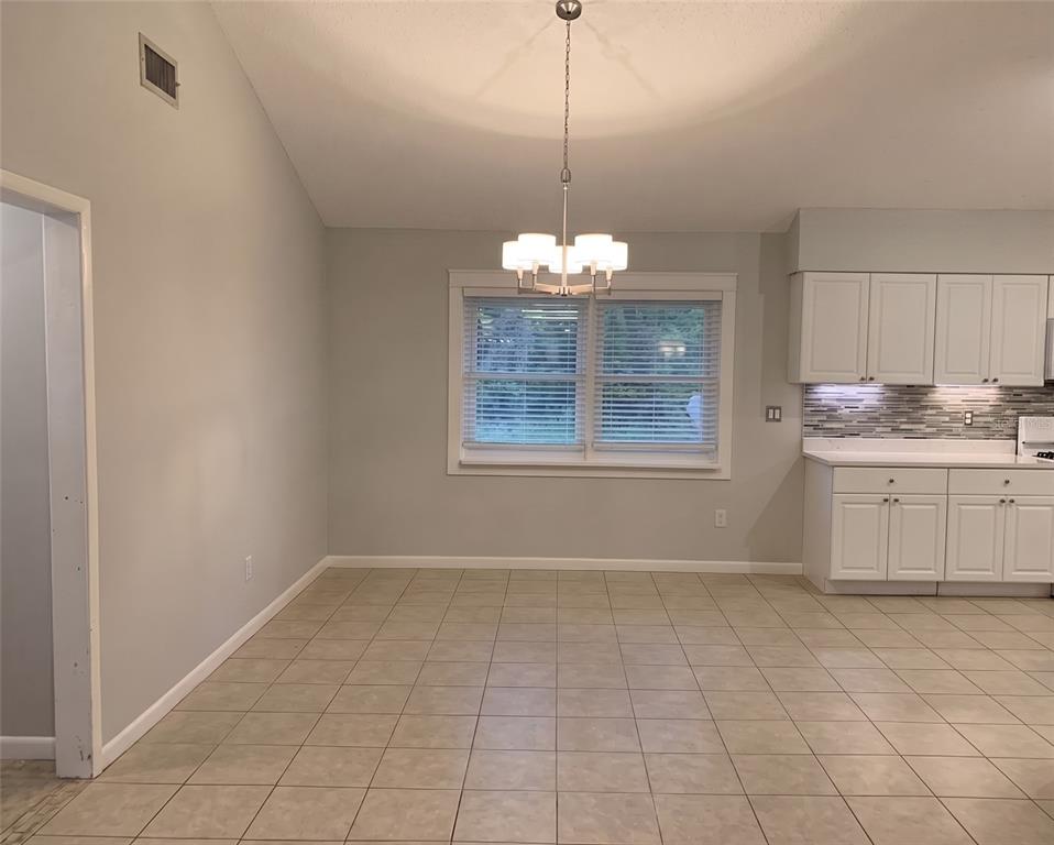 A dining area with tile flooring, a chandelier, and a window next to a kitchen — 3 ELIZABETH DRIVE E, PALM COAST, FL