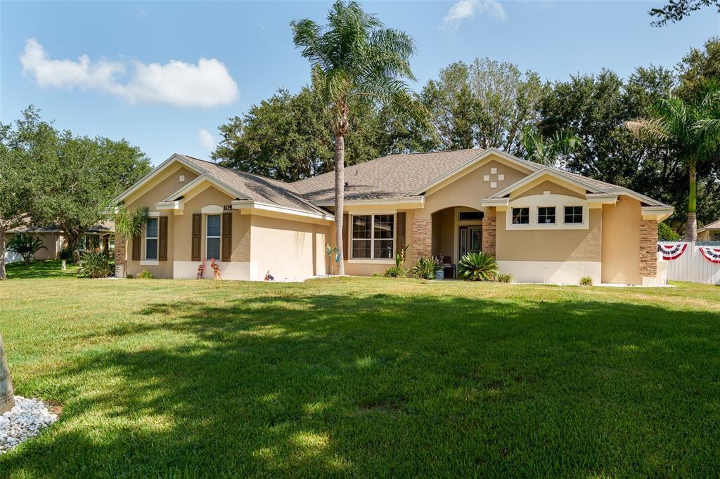 A single-story tan stucco house with a shingled roof and a large front lawn — 10501 VIA COMO COURT, CLERMONT, FL
