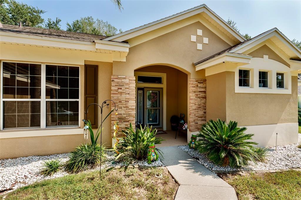 The exterior of a tan house features stone accents, a covered entryway, and white trim — 10501 VIA COMO COURT, CLERMONT, FL