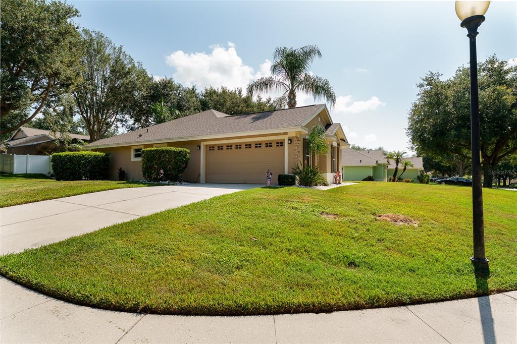 A single-story house with a tan exterior, a two-car garage, and a concrete driveway — 10501 VIA COMO COURT, CLERMONT, FL