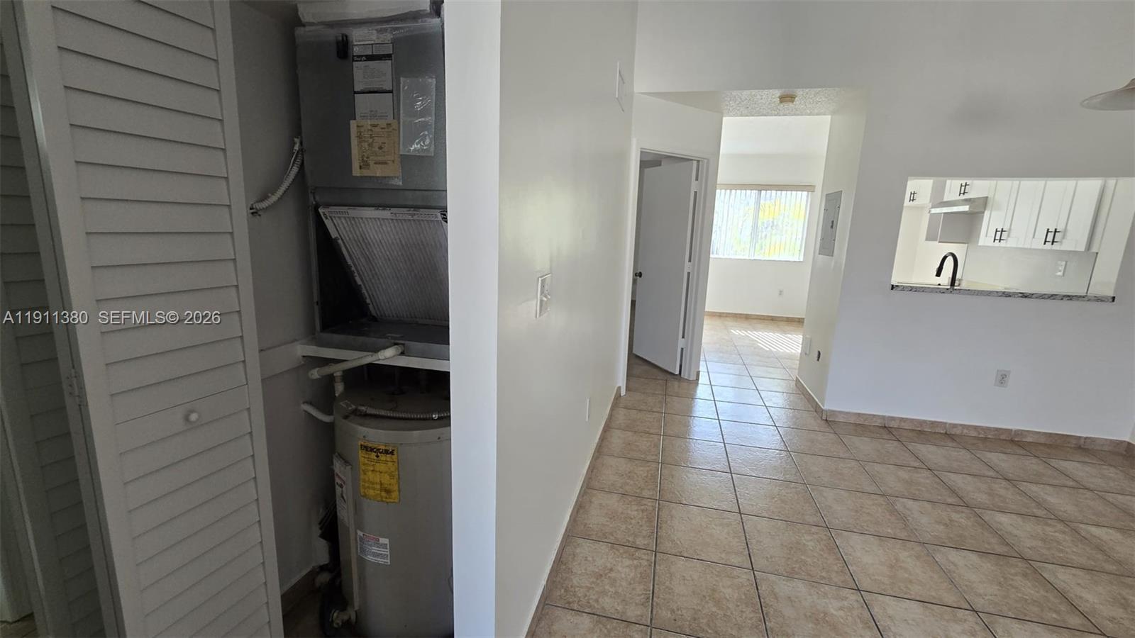 A utility closet containing an HVAC unit and water heater sits beside a tiled hallway — 13120 SW 64th Ter # 1510, Miami FL 33183, MIAMI, FL