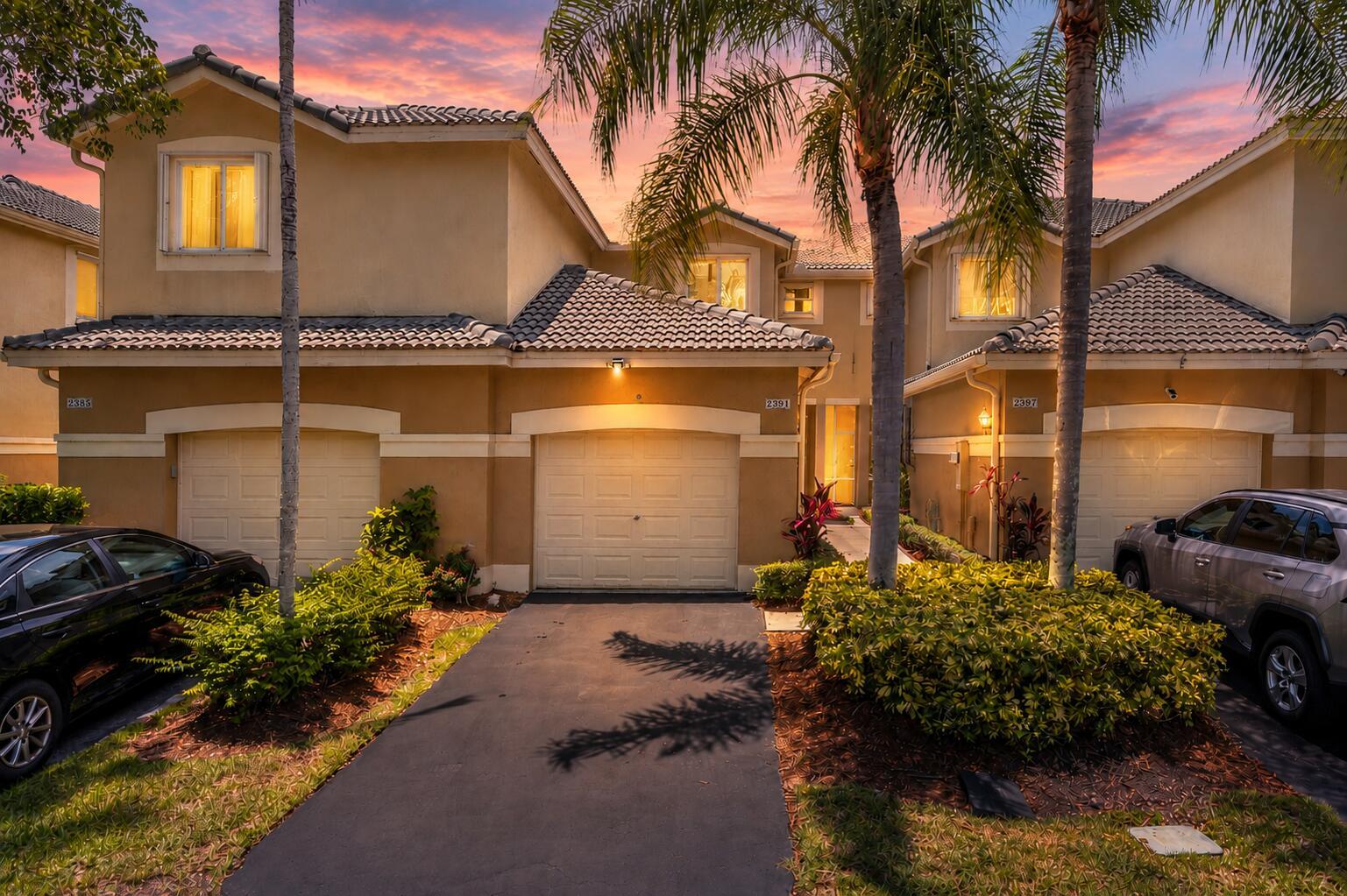 A row of three tan townhouses with garages and palm trees at sunset — 2391 Pasadena Way, Weston FL 33327, WESTON, FL