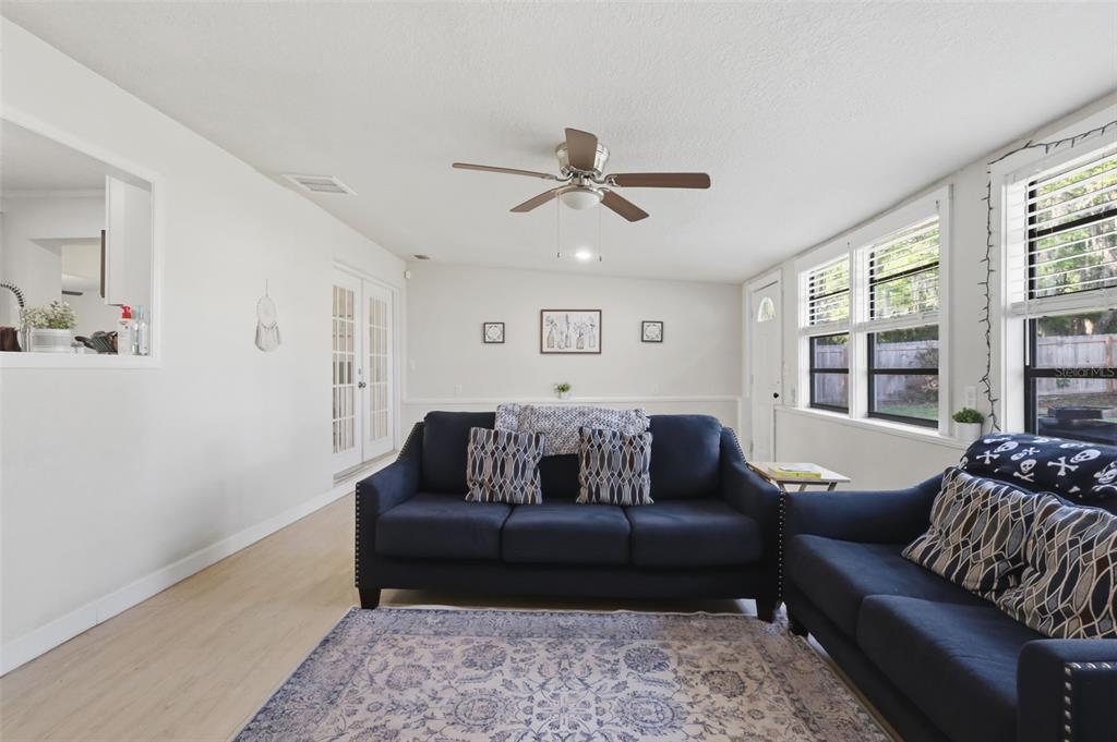 A living room features two dark blue sofas, a patterned rug, and a ceiling fan — 112 EDWARDS AVENUE, ORANGE CITY, FL