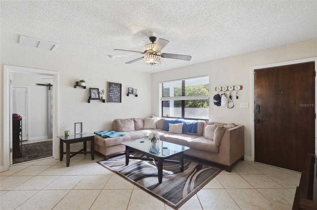 A living room features a beige sectional sofa, a glass coffee table, and tile flooring — 112 EDWARDS AVENUE, ORANGE CITY, FL
