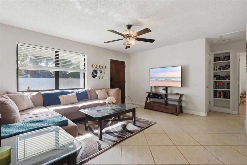 A living room features a sectional sofa, a television on a stand, and tile flooring — 112 EDWARDS AVENUE, ORANGE CITY, FL