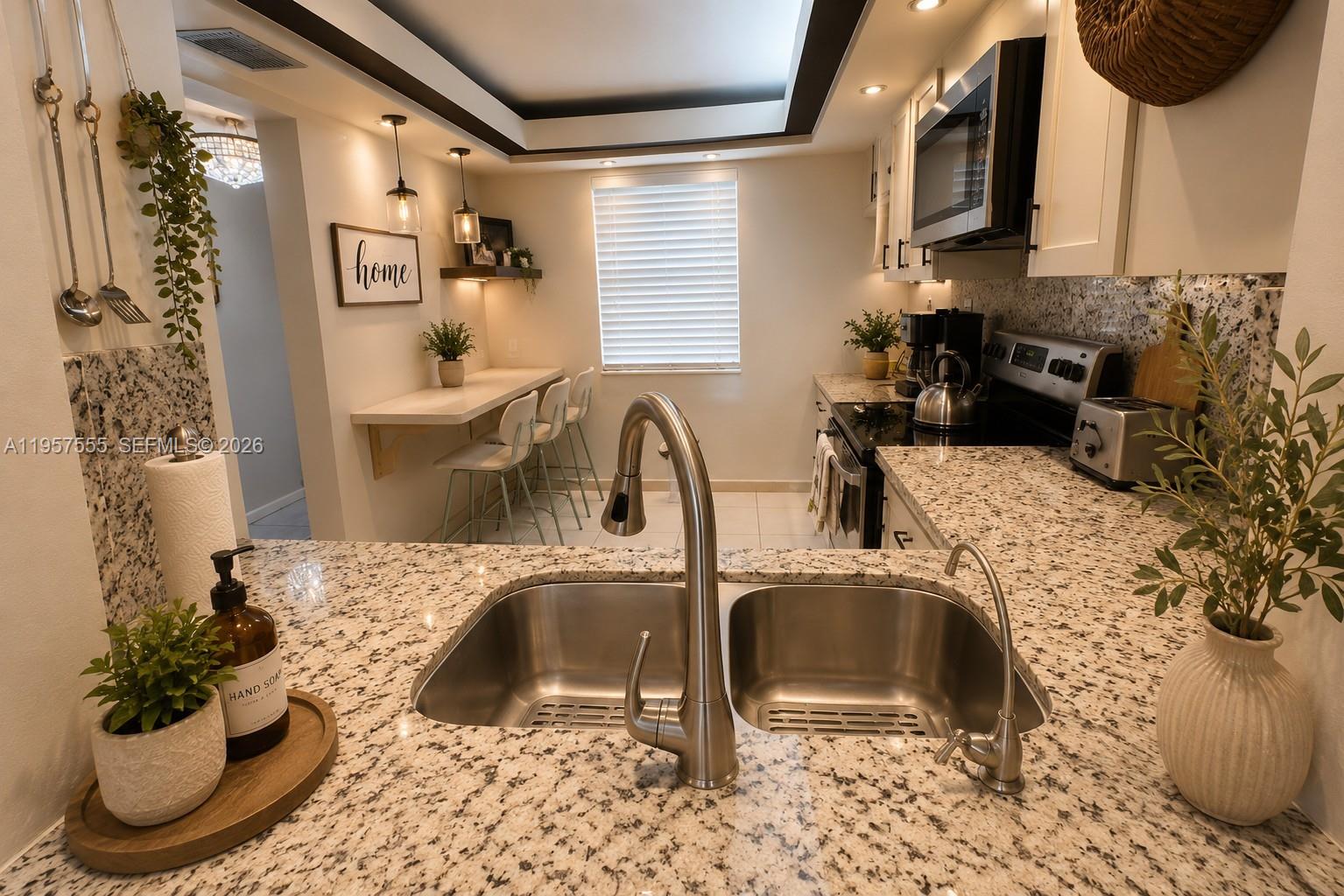 A kitchen features granite countertops, a double-basin sink, white cabinetry, and a breakfast bar area — 3910 Inverrary Blvd # B, Lauderhill FL 33319, LAUDERHILL, FL