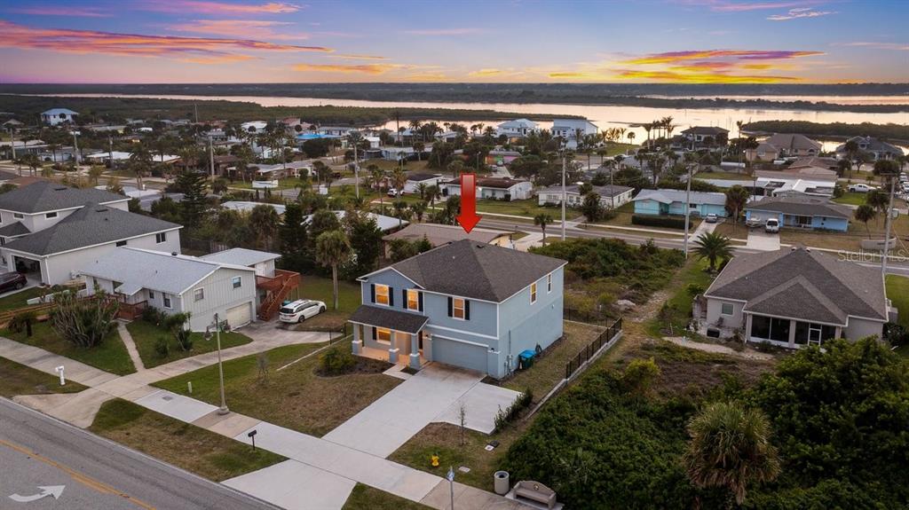 An aerial view shows a two-story light blue house with a driveway and surrounding neighborhood — 3828 S ATLANTIC AVENUE, DAYTONA BEACH SHORES, FL