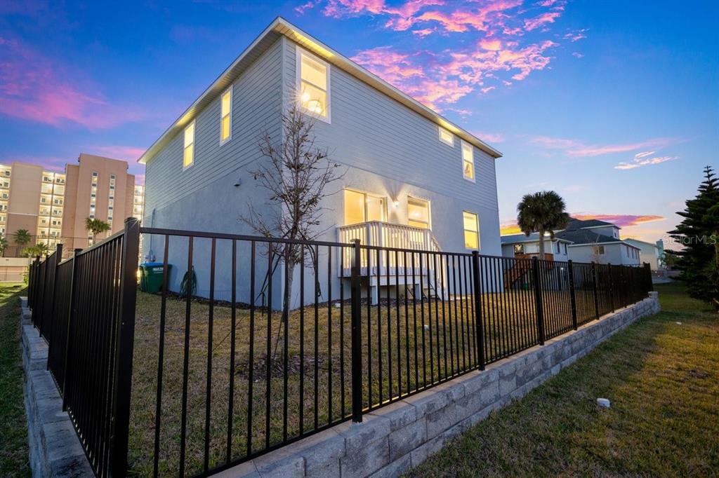 The exterior of a two-story house features light blue siding, a small deck, and fencing — 3828 S ATLANTIC AVENUE, DAYTONA BEACH SHORES, FL