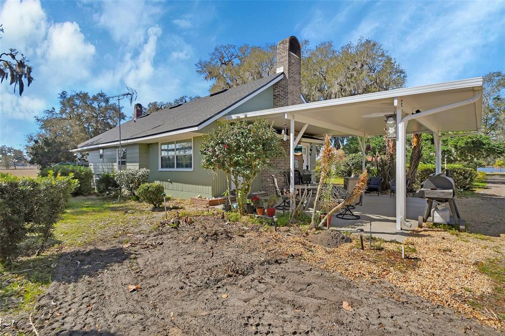 A light green house with a brick chimney and a covered patio area — 1403 BLACKWELDER ROAD, DE LEON SPRINGS, FL