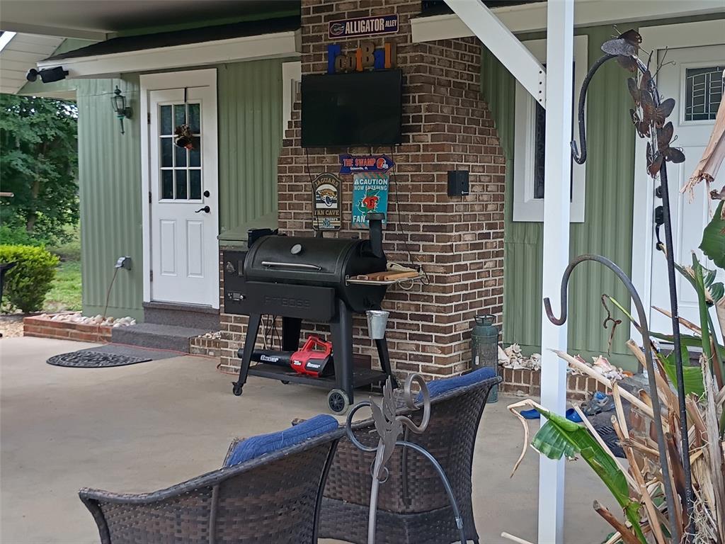 A covered patio features a brick fireplace, a black grill, and outdoor seating — 1403 BLACKWELDER ROAD, DE LEON SPRINGS, FL