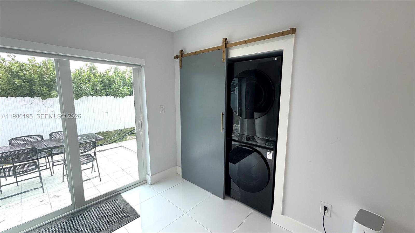 A laundry closet with a sliding barn door sits beside a sliding glass patio door — 14401 Boggs Dr, Miami FL 33176, MIAMI, FL