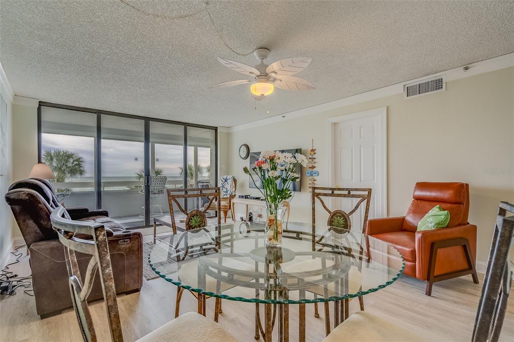 A living and dining area features a glass table, leather chairs, and a balcony view — 17900 GULF BOULEVARD UNIT 2E, REDINGTON SHORES, FL