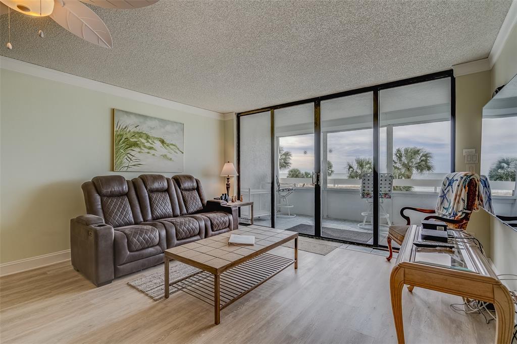 A living room features a brown leather sofa, tile coffee table, and sliding glass balcony doors — 17900 GULF BOULEVARD UNIT 2E, REDINGTON SHORES, FL