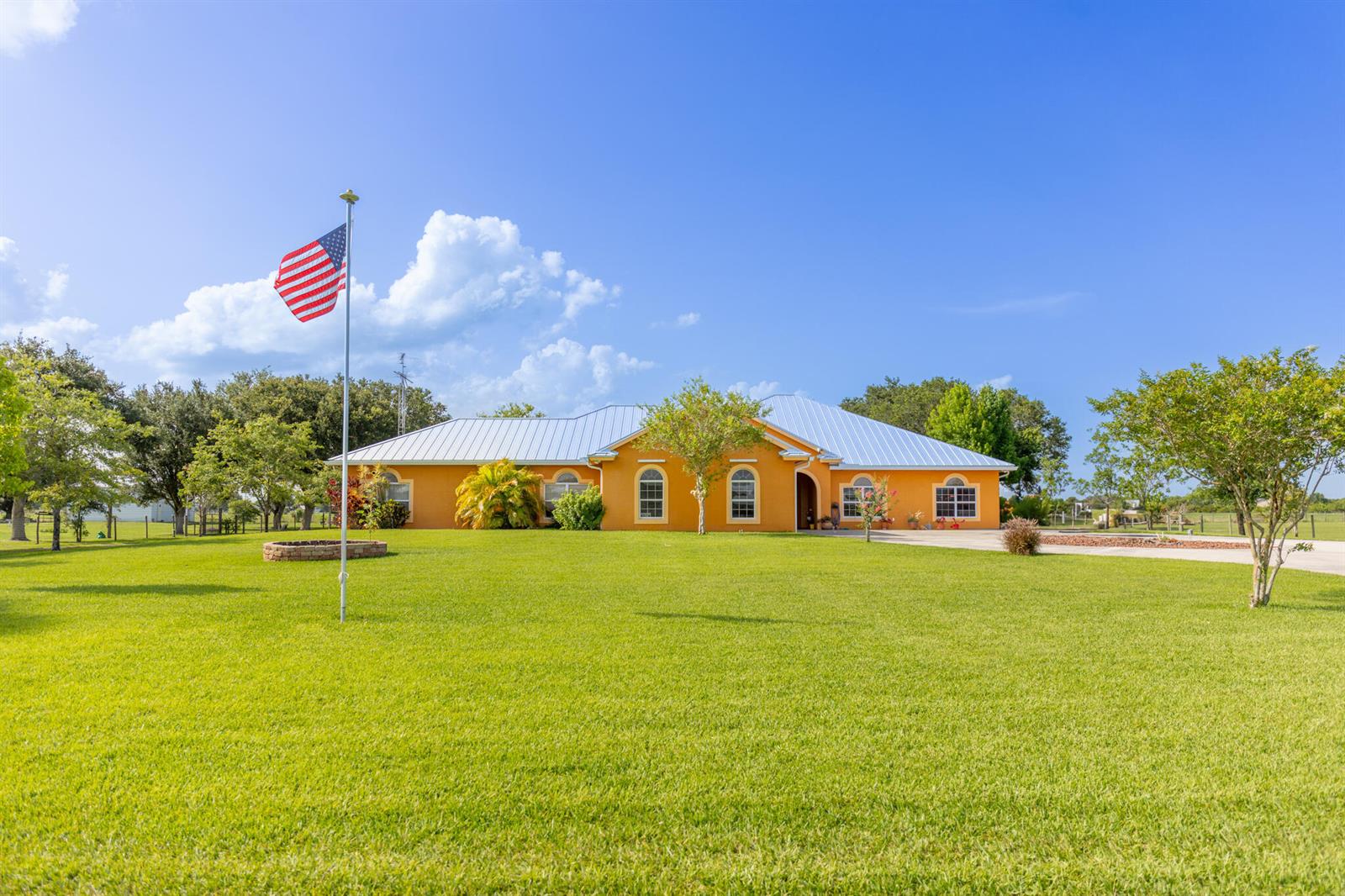 A single-story orange house with a metal roof sits on a large grassy lawn — 7611 SW 21st Parkway, Okeechobee FL 34974, OKEECHOBEE, FL