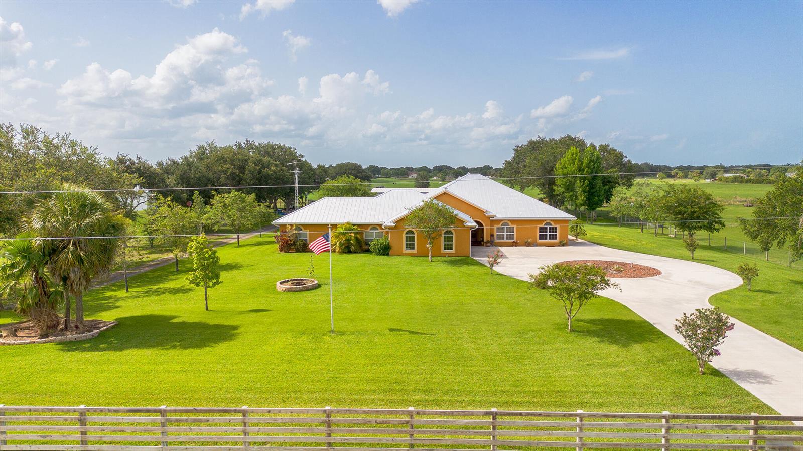 An aerial view of a single-story orange house with a metal roof and large lawn — 7611 SW 21st Parkway, Okeechobee FL 34974, OKEECHOBEE, FL