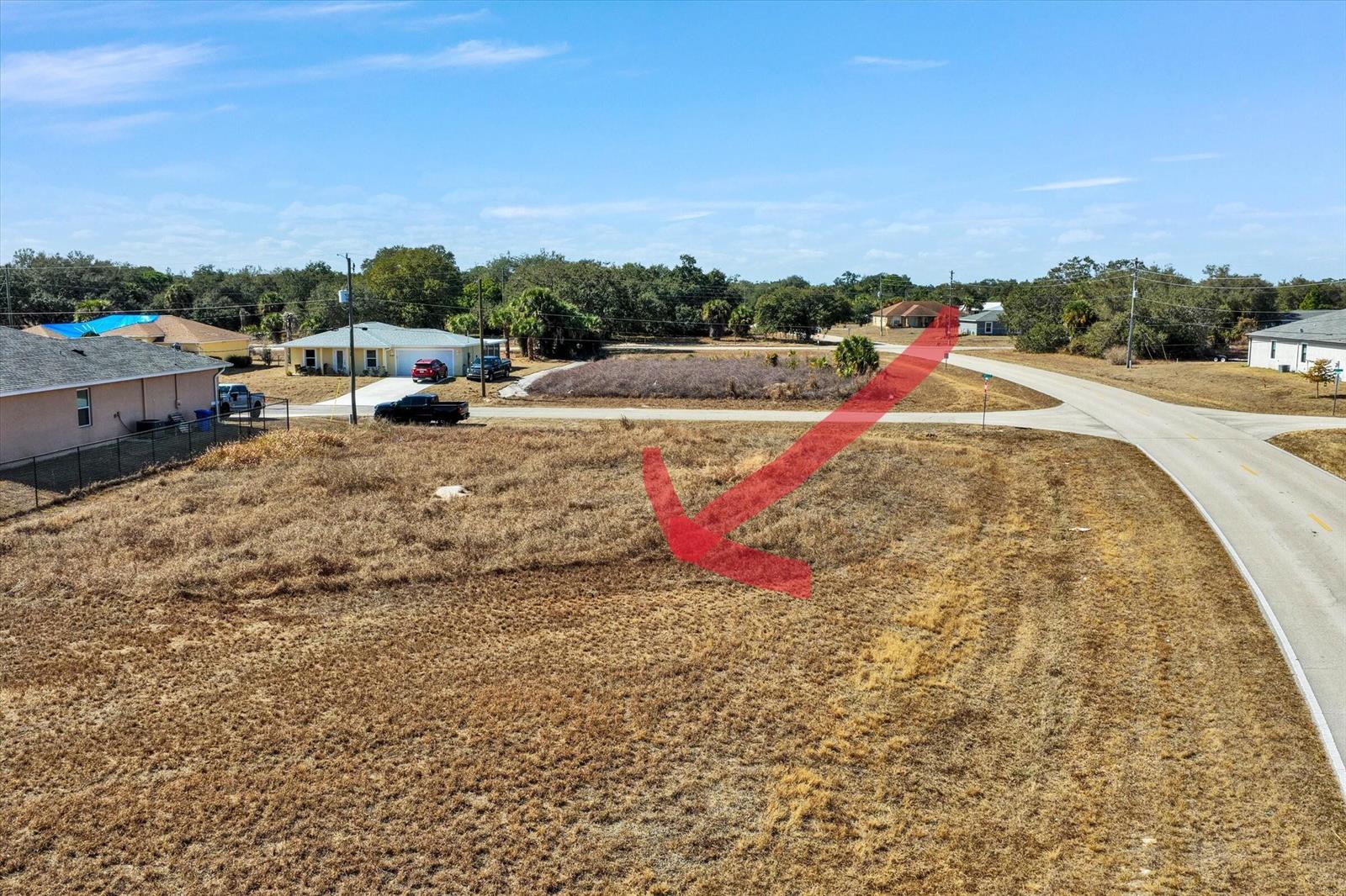 An aerial view shows a vacant, grassy corner lot bordered by paved roads — Blk 34 Naples Street, FL 33935, FL