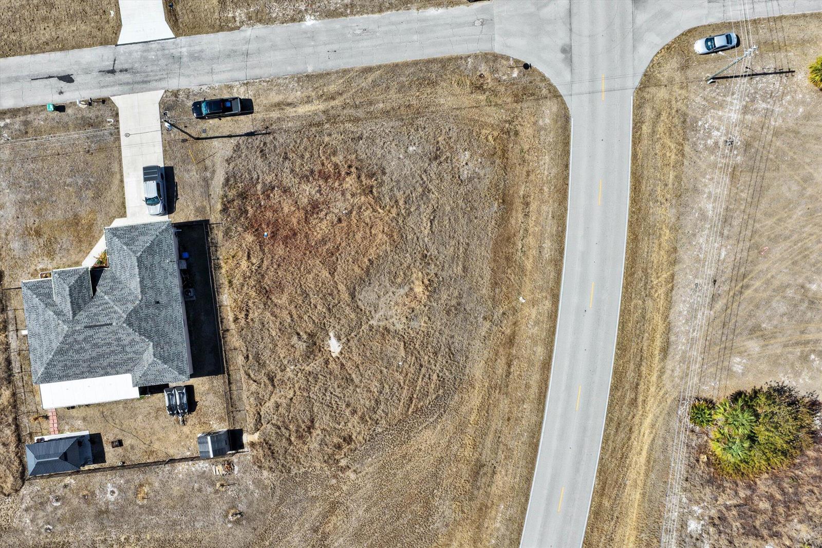 An aerial view shows a house with a fenced yard next to an empty lot — Blk 34 Naples Street, FL 33935, FL