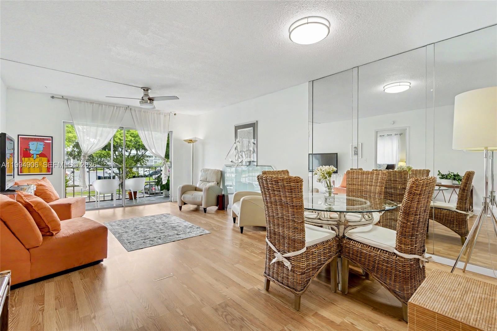 A living and dining area features orange sofas, wicker chairs, and a mirrored wall — 1000 Hillcrest Ct # 215, Hollywood FL 33021, HOLLYWOOD, FL
