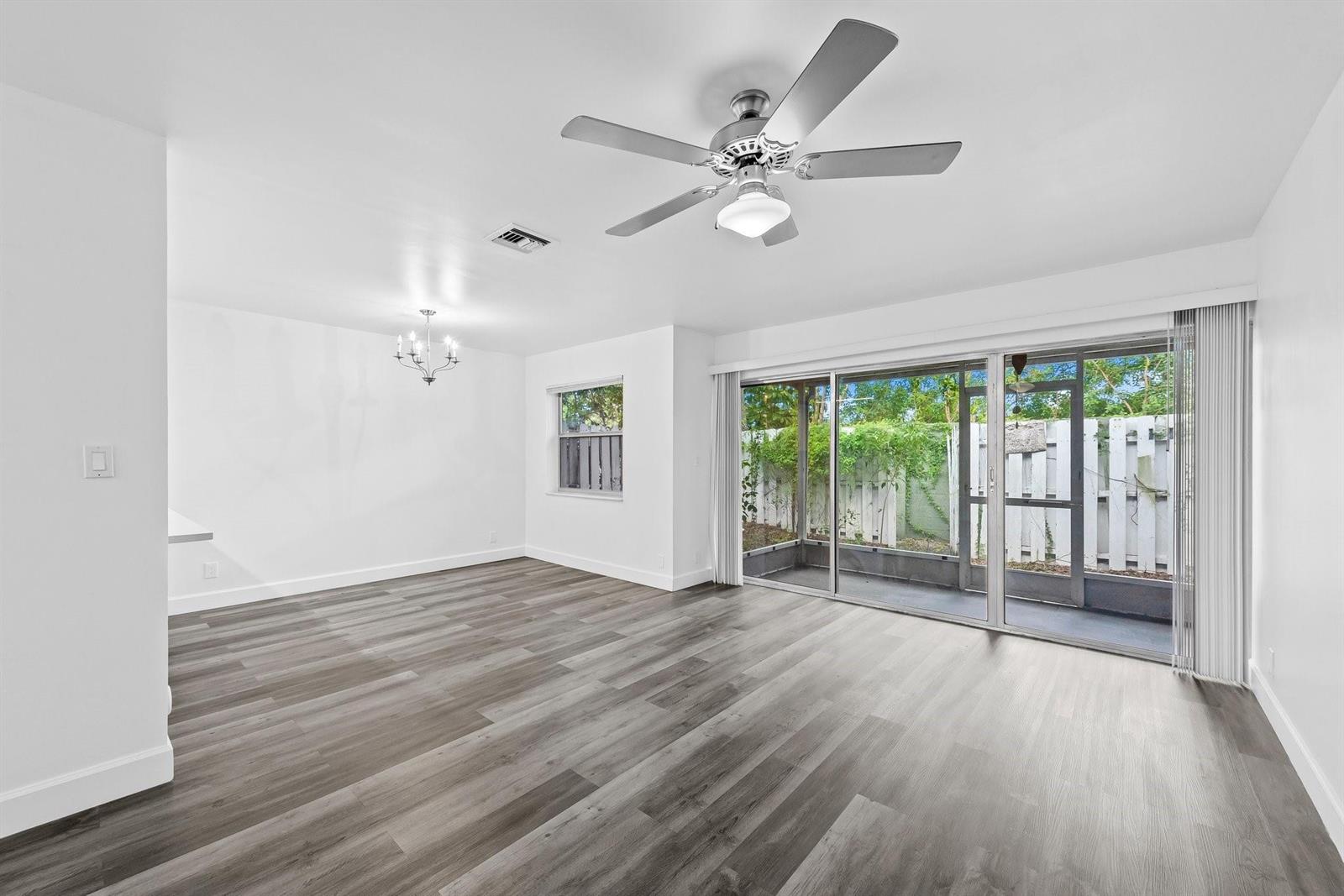 A bright living room features wood-look flooring, a ceiling fan, and sliding glass patio doors — 822 Crystal Lake Drive # 822, Deerfield Beach FL 33064, DEERFIELD BEACH, FL