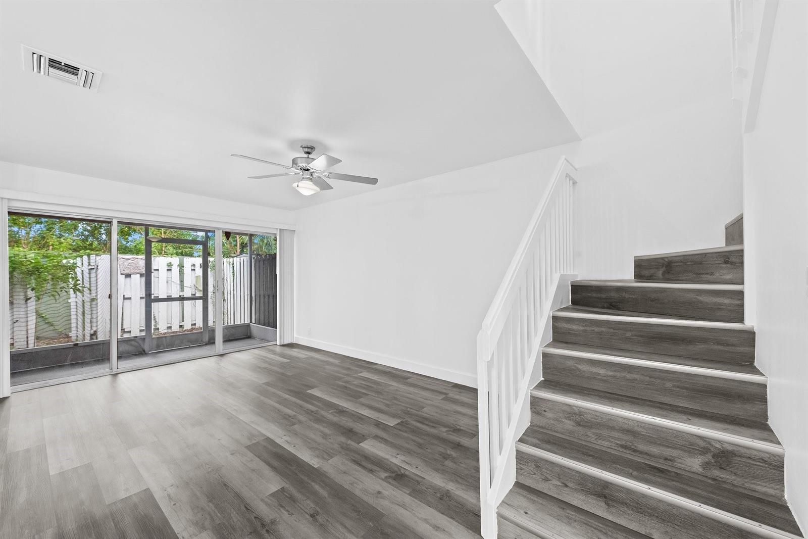 A living room with wood-look flooring, a ceiling fan, and stairs leading to an upper level — 822 Crystal Lake Drive # 822, Deerfield Beach FL 33064, DEERFIELD BEACH, FL