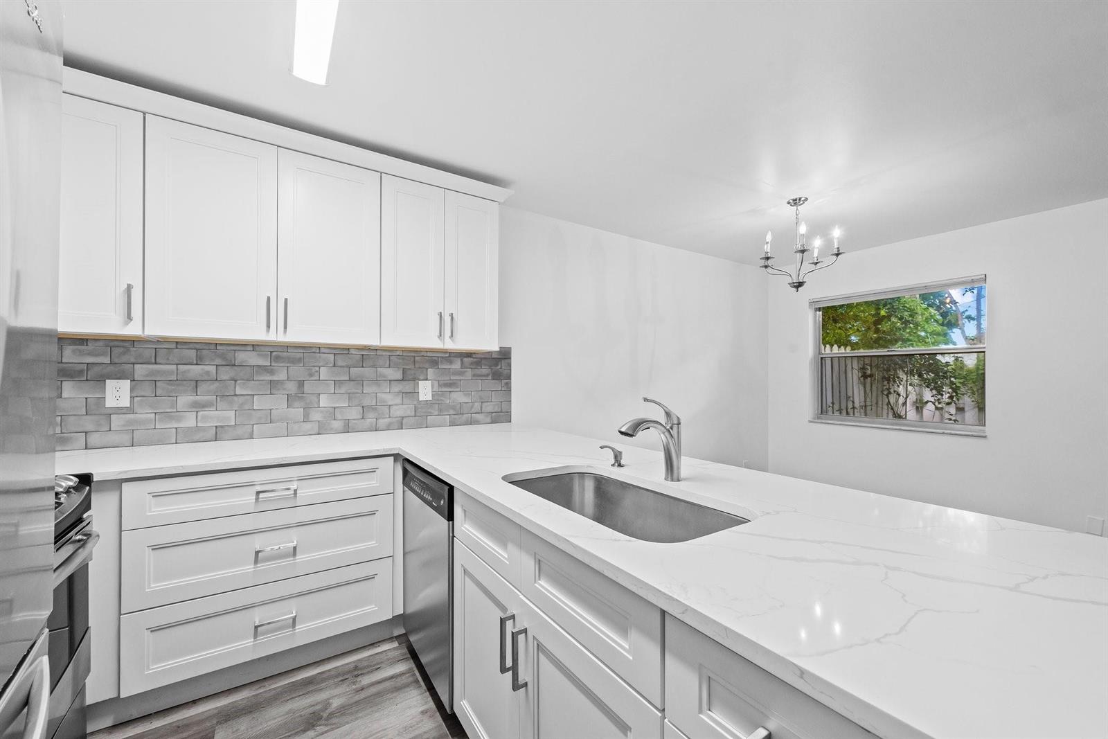 A kitchen features white cabinets, a gray subway tile backsplash, and a white quartz countertop — 822 Crystal Lake Drive # 822, Deerfield Beach FL 33064, DEERFIELD BEACH, FL