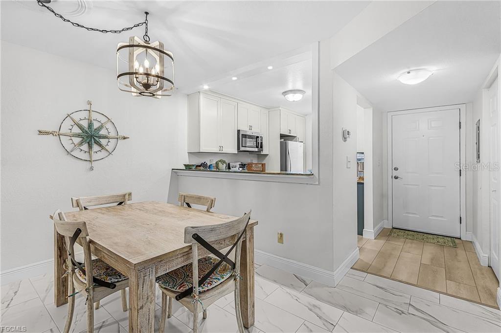A dining area with a wooden table and chandelier sits adjacent to a white kitchen — 14461 LAKEWOOD TRACE COURT UNIT 103, FORT MYERS, FL