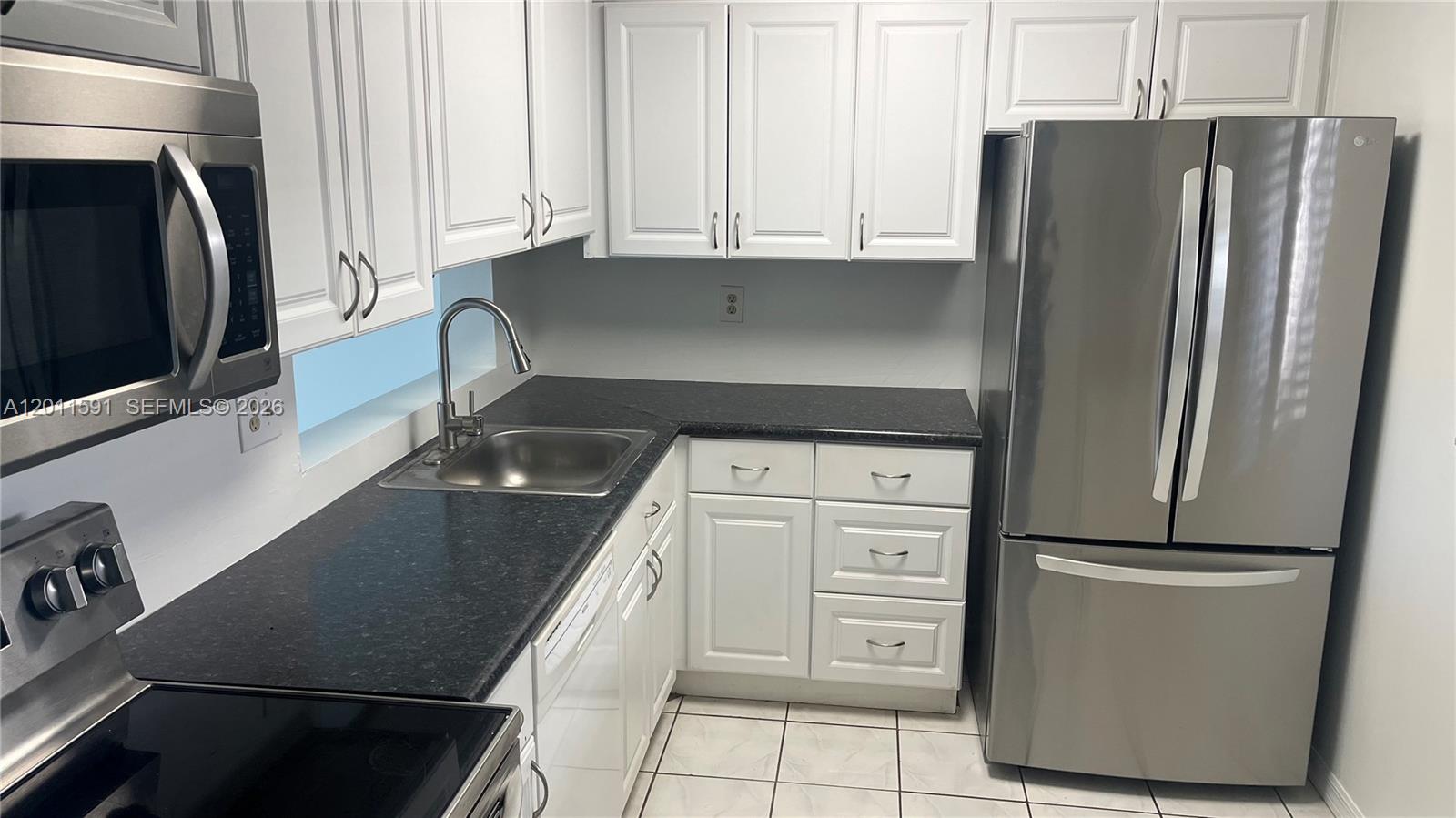 A kitchen features white cabinets, dark countertops, stainless steel appliances, and tiled flooring — 8540 SW 133rd Ave Rd # 316, Miami FL 33183, MIAMI, FL