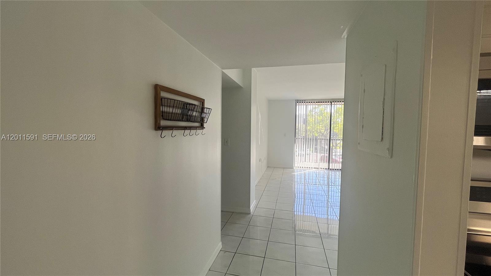A hallway with white tile floors leads to a living area with a sliding glass door — 8540 SW 133rd Ave Rd # 316, Miami FL 33183, MIAMI, FL