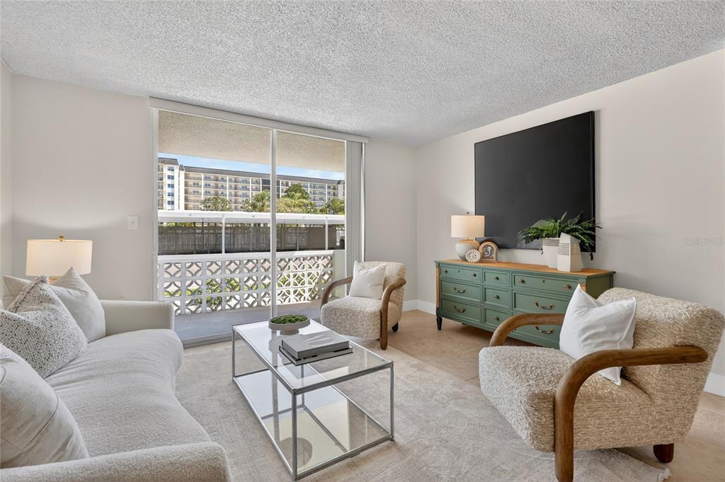 A living room features a glass coffee table, two armchairs, a sofa, and a green dresser — 9 FORBES PLACE PLACE UNIT 112, DUNEDIN, FL