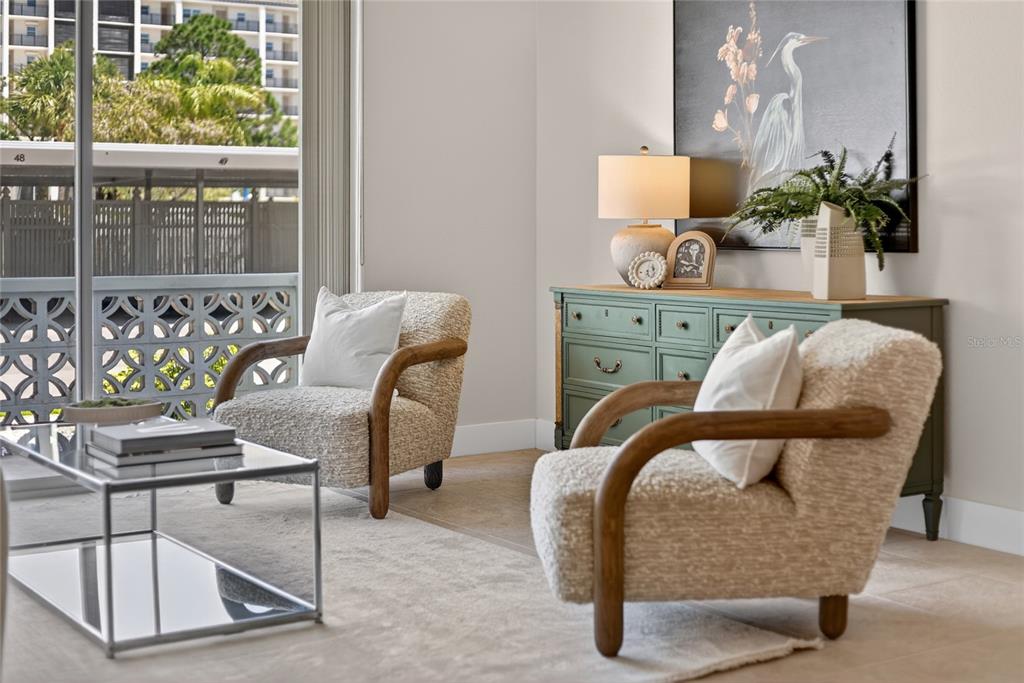 A living area features two textured armchairs, a glass coffee table, and a green dresser — 9 FORBES PLACE PLACE UNIT 112, DUNEDIN, FL