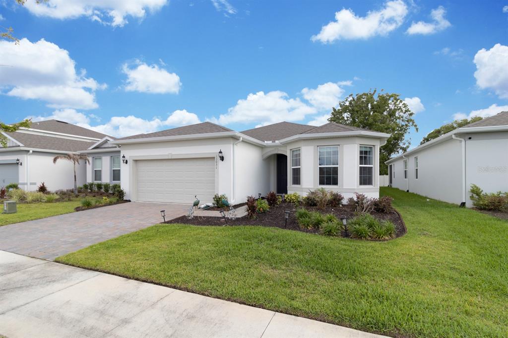 A single-story house with a white stucco exterior, a two-car garage, and a landscaped yard — 13031 SKYWAY LANE, ORLANDO, FL