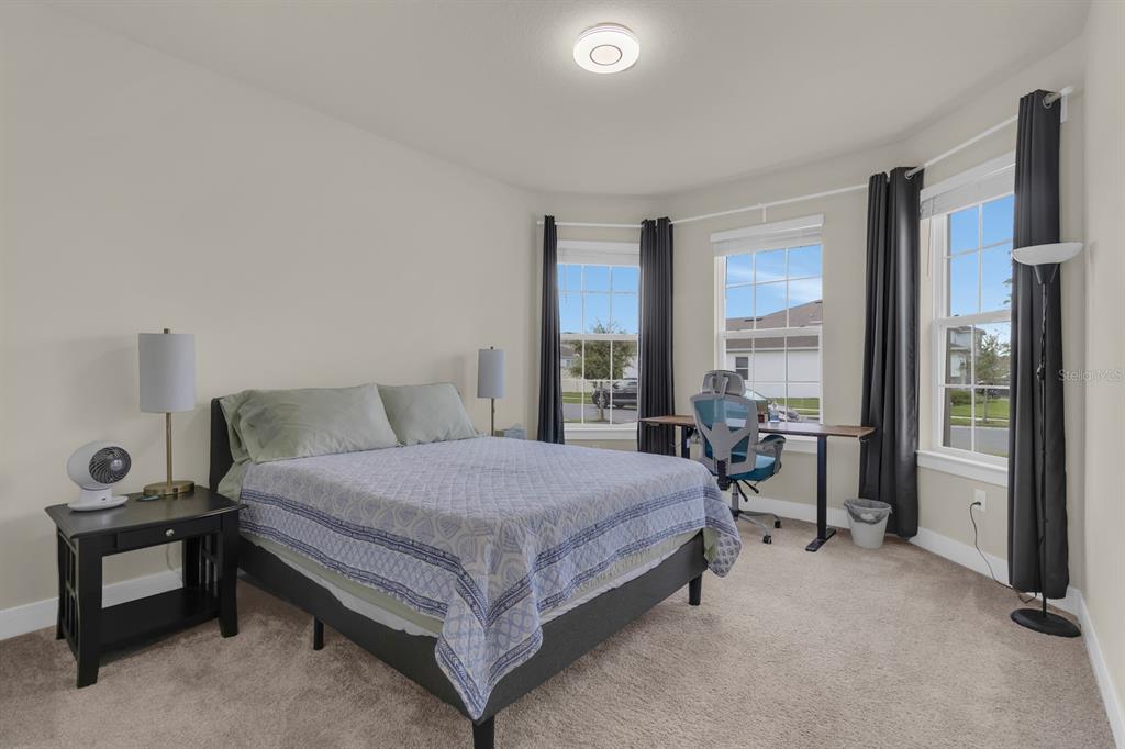 A bedroom features a bed, a desk with a chair, and windows with dark curtains — 13031 SKYWAY LANE, ORLANDO, FL