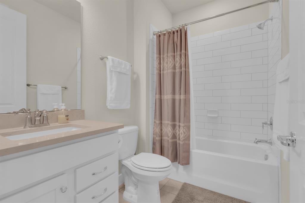A bathroom features a white vanity, a toilet, and a shower-tub combo with white tile — 13031 SKYWAY LANE, ORLANDO, FL