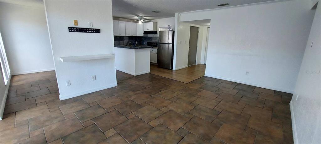 A kitchen with white cabinets and stainless steel appliances opens to a tiled living area — 2625 STATE ROAD 590 UNIT 2721, CLEARWATER, FL