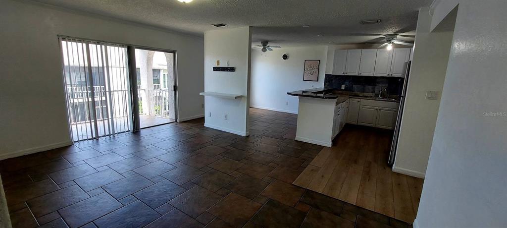 An open-concept living area features tile flooring, a kitchen with white cabinets, and a balcony — 2625 STATE ROAD 590 UNIT 2721, CLEARWATER, FL