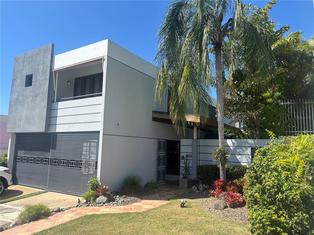 A two-story modern house with a gray facade, a slatted garage door, and a palm tree — W 4-14 CALDERÓN DE LA BARCA, SAN JUAN, PR