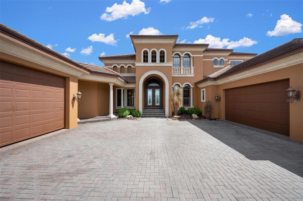 A tan two-story house with a paved driveway and two attached garages under a blue sky — 14115 11TH TERRACE NE, BRADENTON, FL