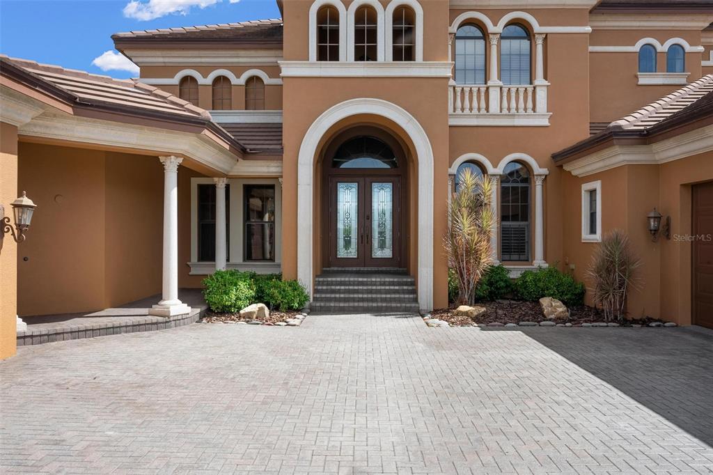 A paved driveway leads to the arched entryway of a two-story stucco home — 14115 11TH TERRACE NE, BRADENTON, FL