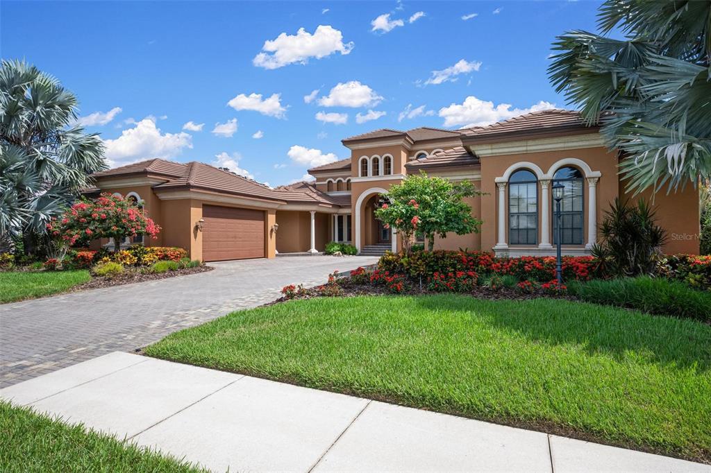 A single-story stucco house with a tile roof, arched windows, and a paved driveway — 14115 11TH TERRACE NE, BRADENTON, FL