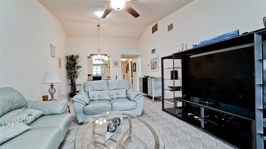 A living room features two light blue leather sofas, a glass coffee table, and carpeted flooring — 6507 HERITAGE LANE UNIT 2605, BRADENTON, FL