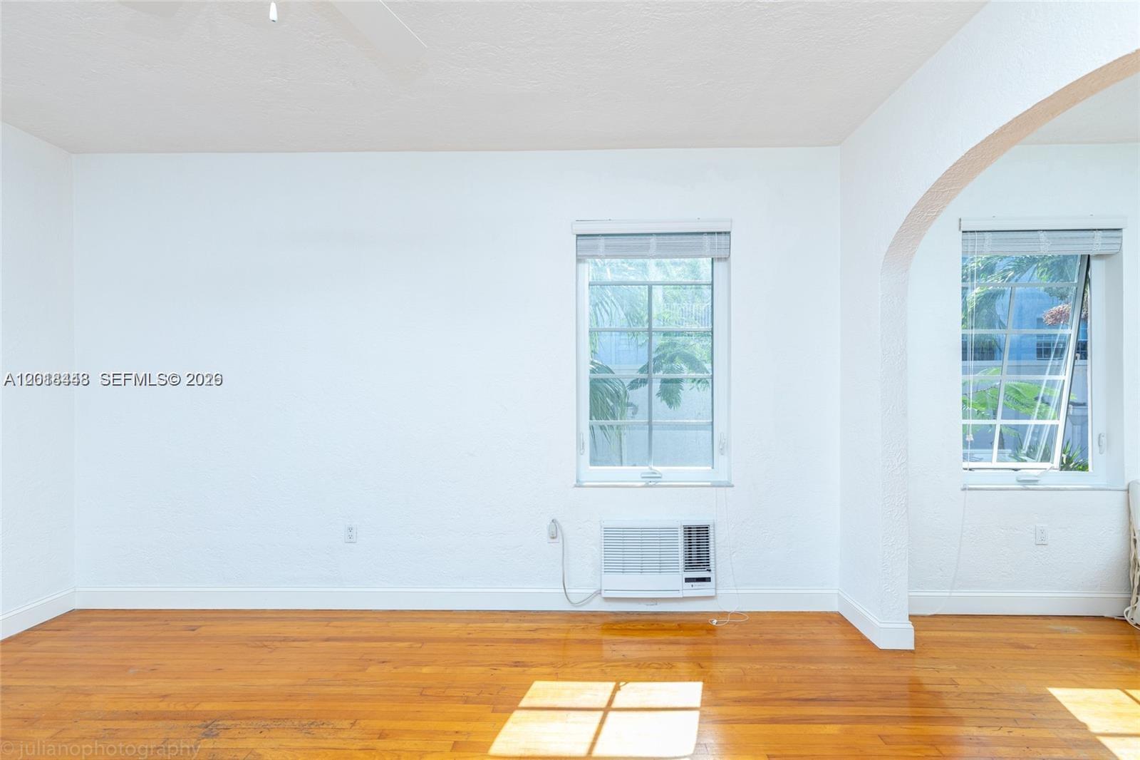 A room with white walls, hardwood floors, two windows, and a wall-mounted air conditioner — 732 Euclid Ave # 6, Miami Beach FL 33139, MIAMI BEACH, FL