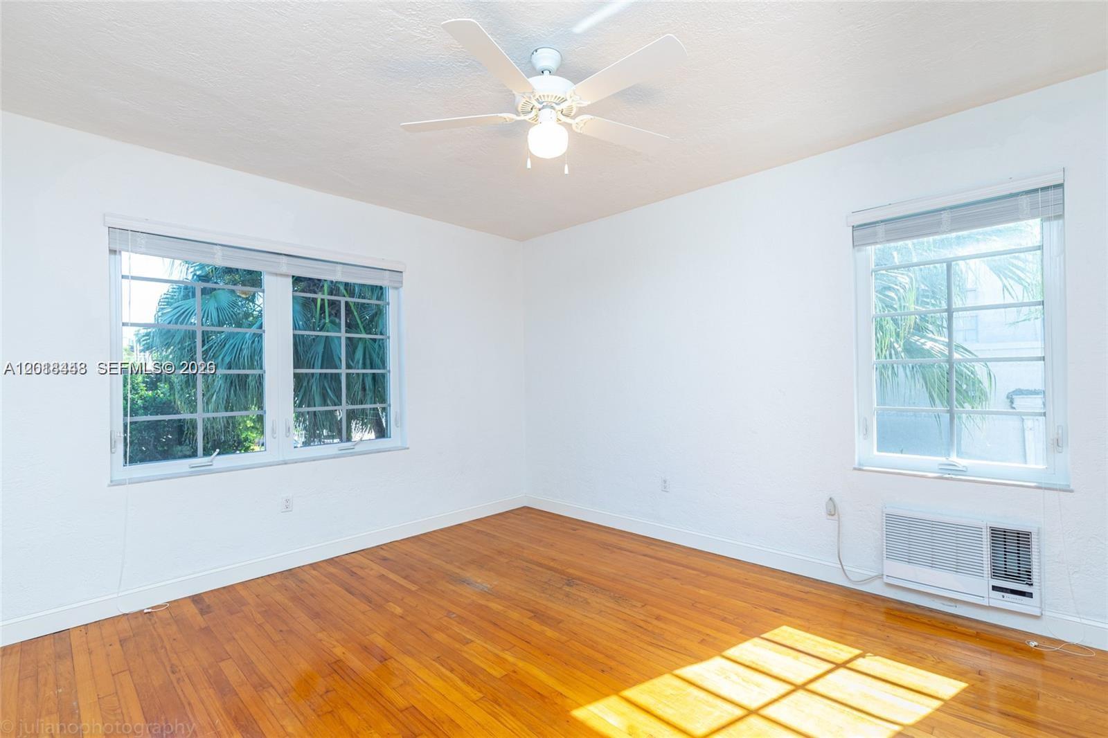 An empty bedroom features white walls, hardwood floors, a ceiling fan, and two windows — 732 Euclid Ave # 6, Miami Beach FL 33139, MIAMI BEACH, FL