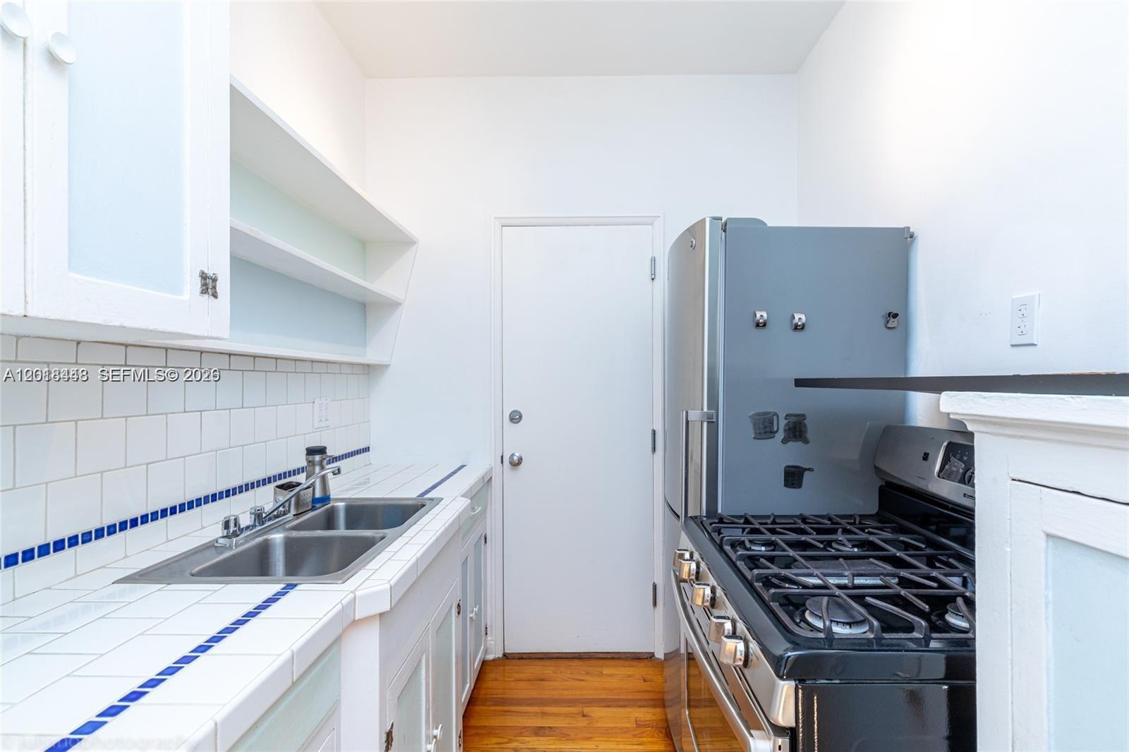 A kitchen features a double sink, tiled countertops, white cabinets, and a gas range — 732 Euclid Ave # 6, Miami Beach FL 33139, MIAMI BEACH, FL