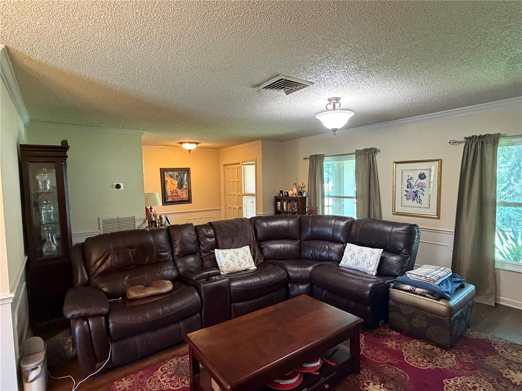 A living room features a large brown leather sectional, a coffee table, and patterned rug — 41 GREENFIELD COURT, WINTER HAVEN, FL
