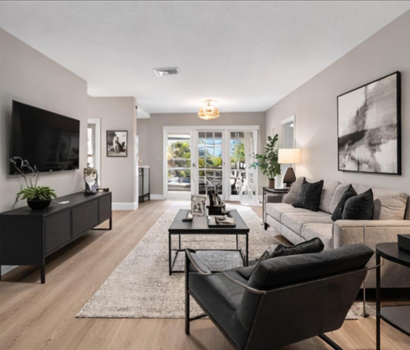 A modern living room features light wood floors, a black media console, and glass doors — 941 Crystal Lake Drive # 311, Deerfield Beach FL 33064, DEERFIELD BEACH, FL
