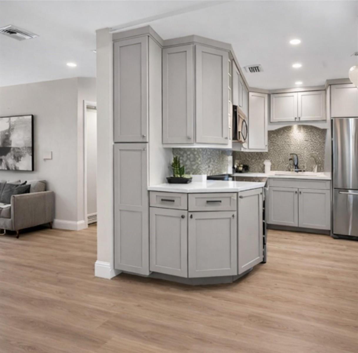 A kitchen with light gray cabinets, white countertops, and wood-look flooring — 941 Crystal Lake Drive # 311, Deerfield Beach FL 33064, DEERFIELD BEACH, FL