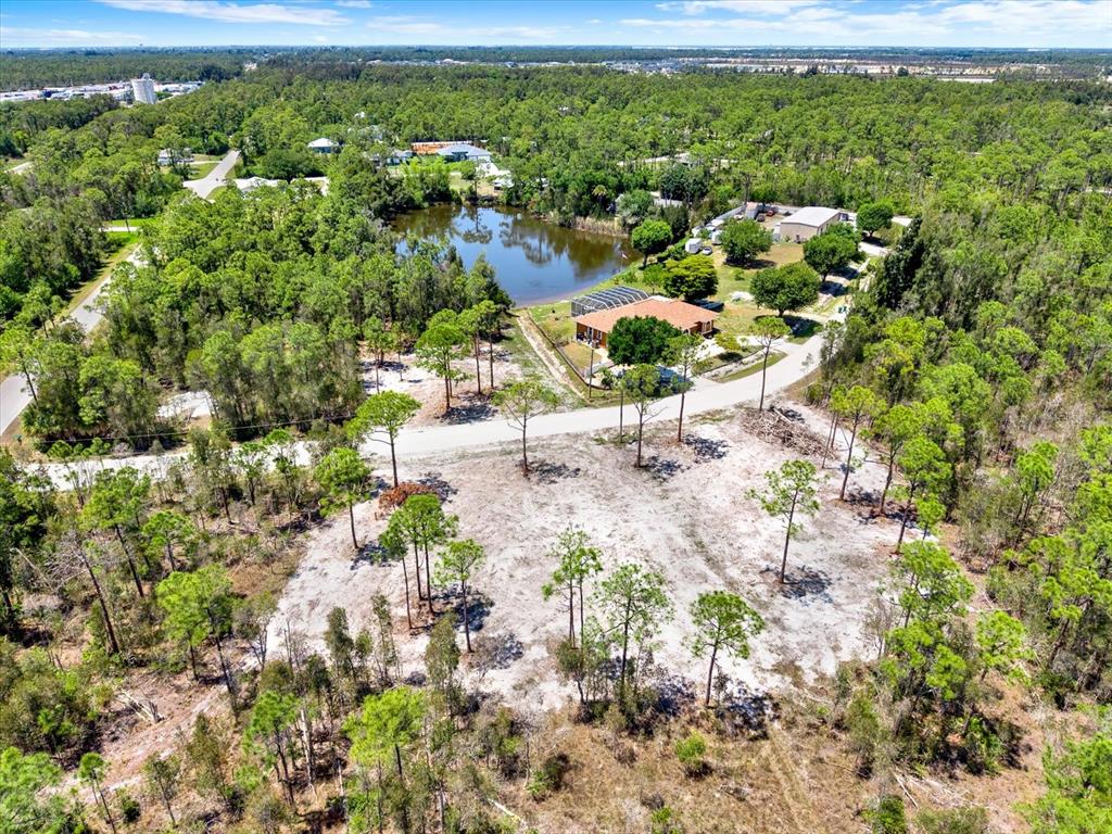 An aerial view shows a house with a pool cage beside a pond and trees — 12278 FINWICK DRIVE, PUNTA GORDA, FL