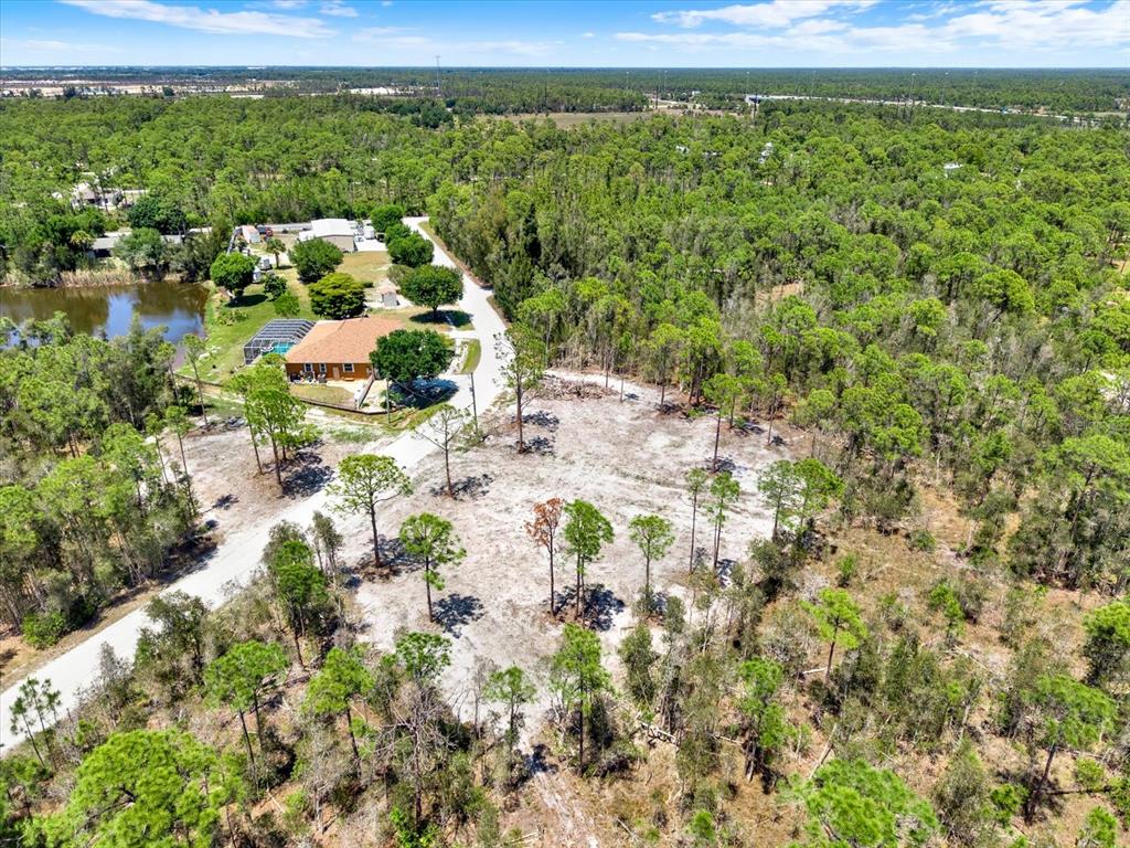 An aerial view shows a house with a pool next to a cleared, wooded lot — 12278 FINWICK DRIVE, PUNTA GORDA, FL